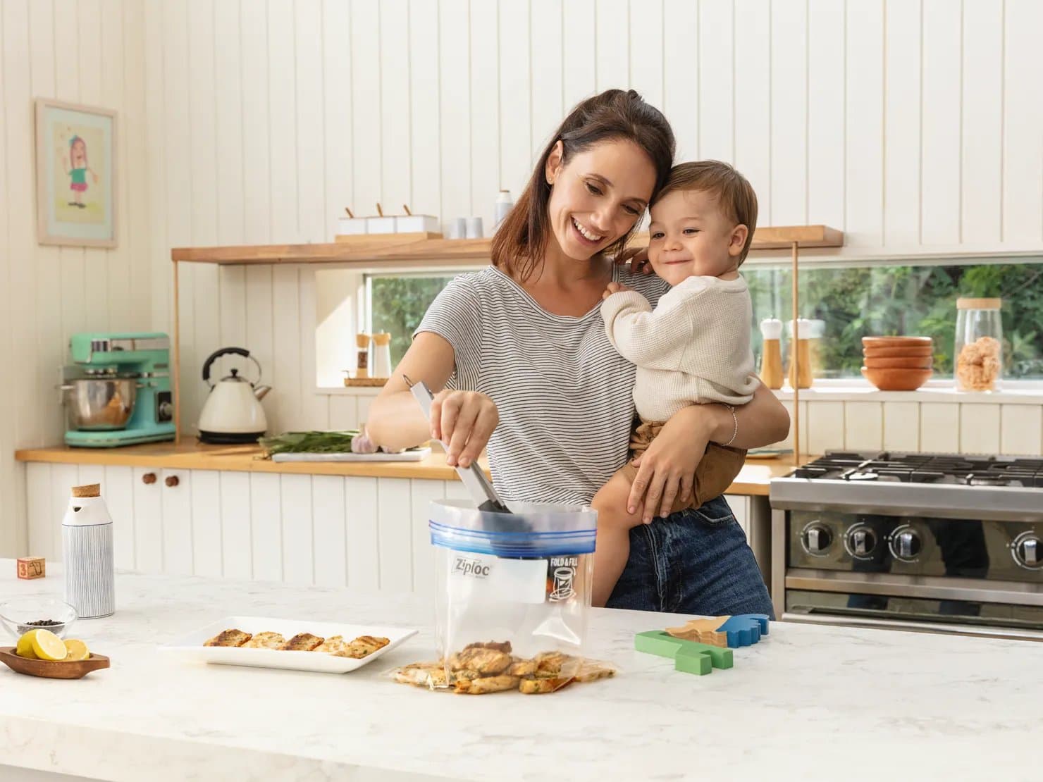 Mother holding child while putting leftovers into Ziploc bag.