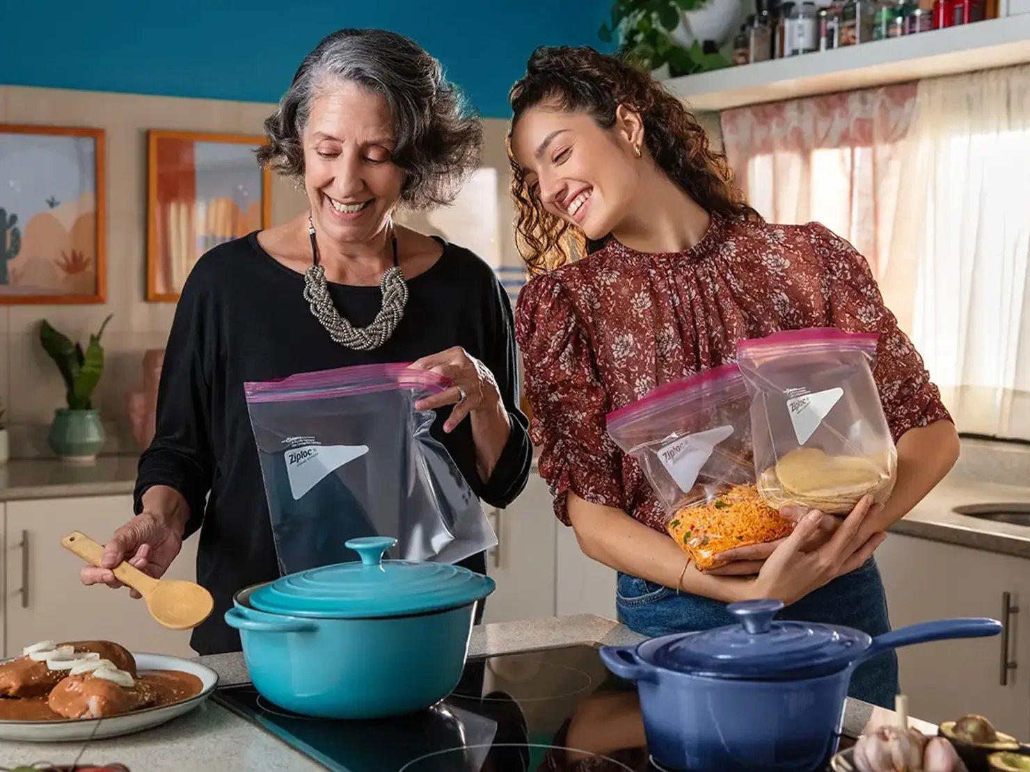 Dos mujeres en una cocina añadiendo comida a bolsas Ziploc®