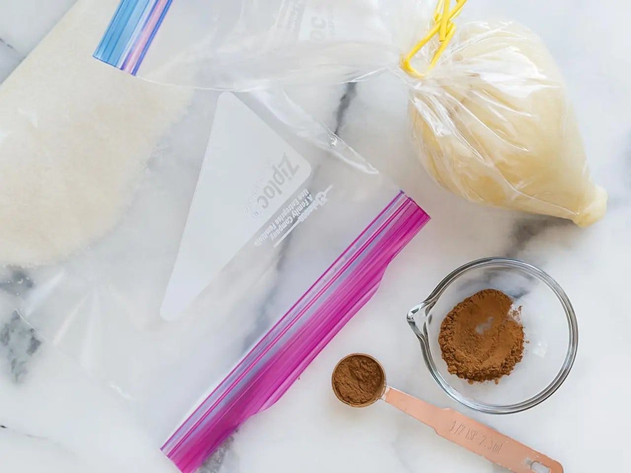 Ziploc bags filled with sugar and icing next to a teaspoon of cinnamon.