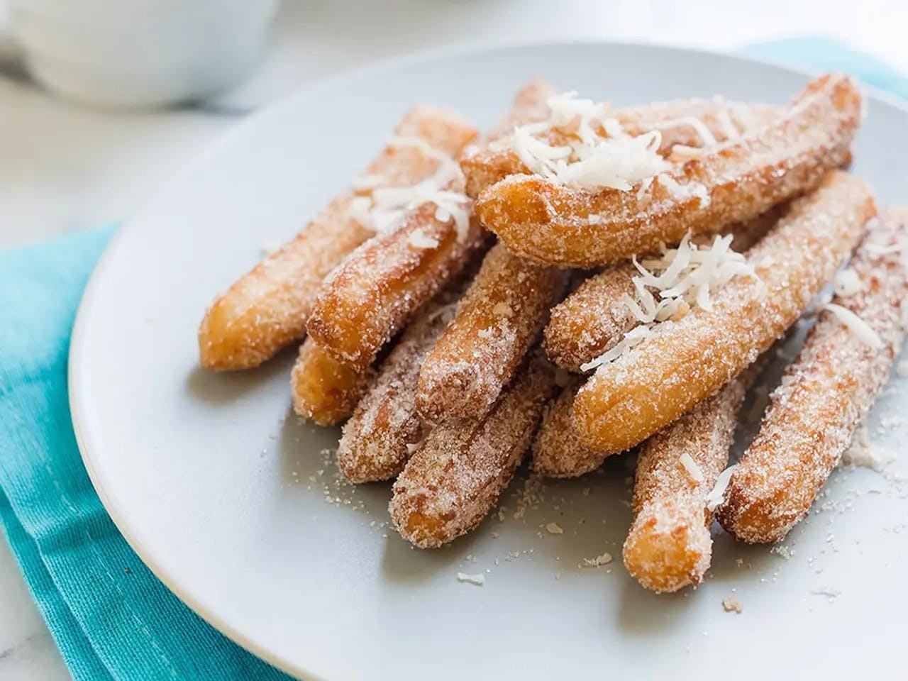 Close up of churros with cinnamon coconut sugar on plate.