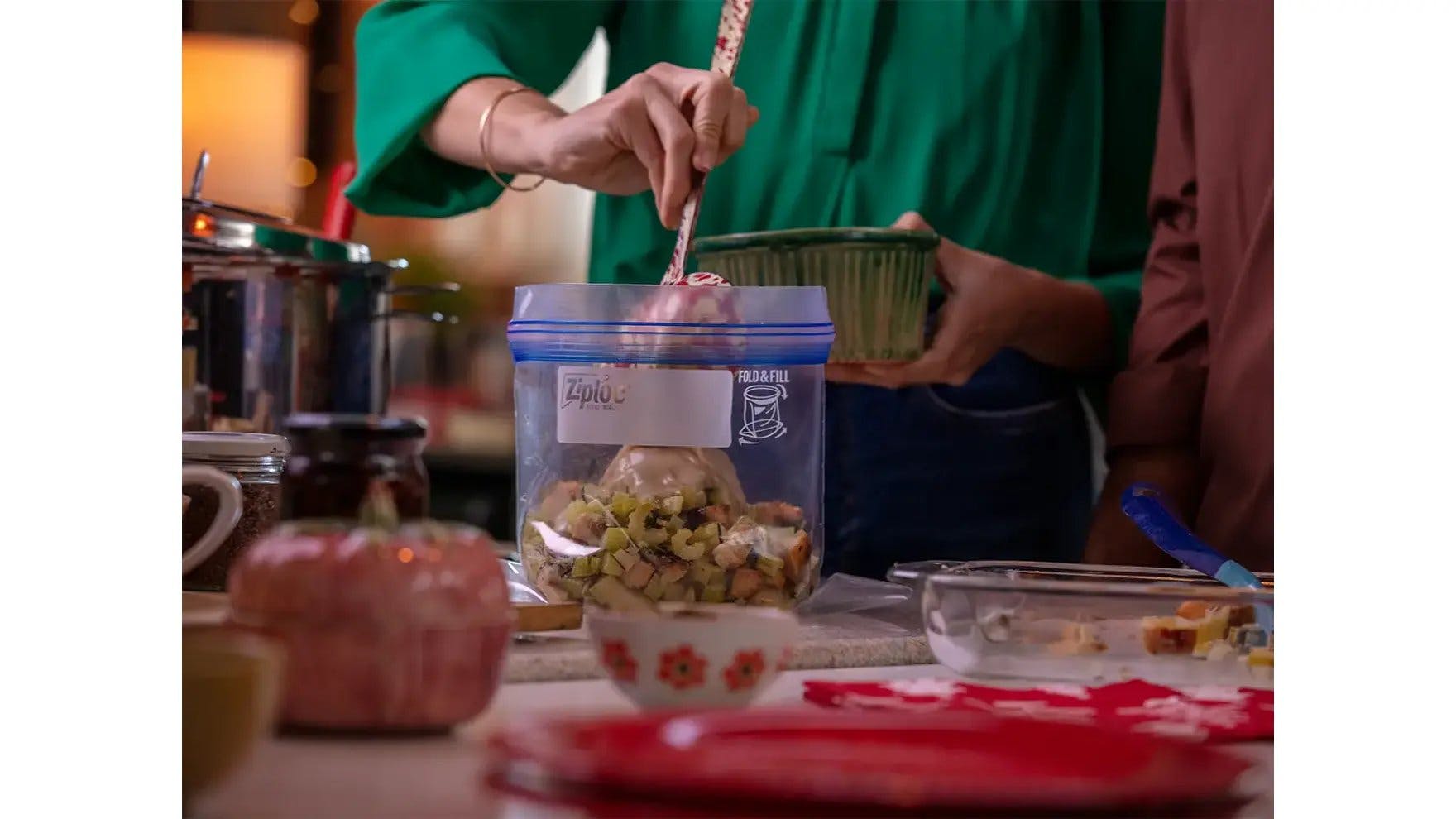 Women in kitchen adding Thanksgiving leftovers to a Ziploc® bag