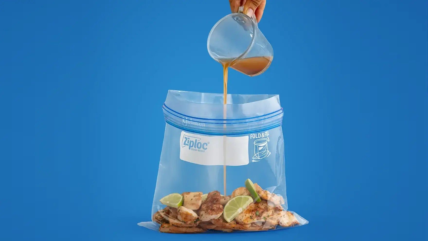 Vertiendo marinada a mano en bolsa para congelar Ziploc de cuarto de galón que contiene pollo